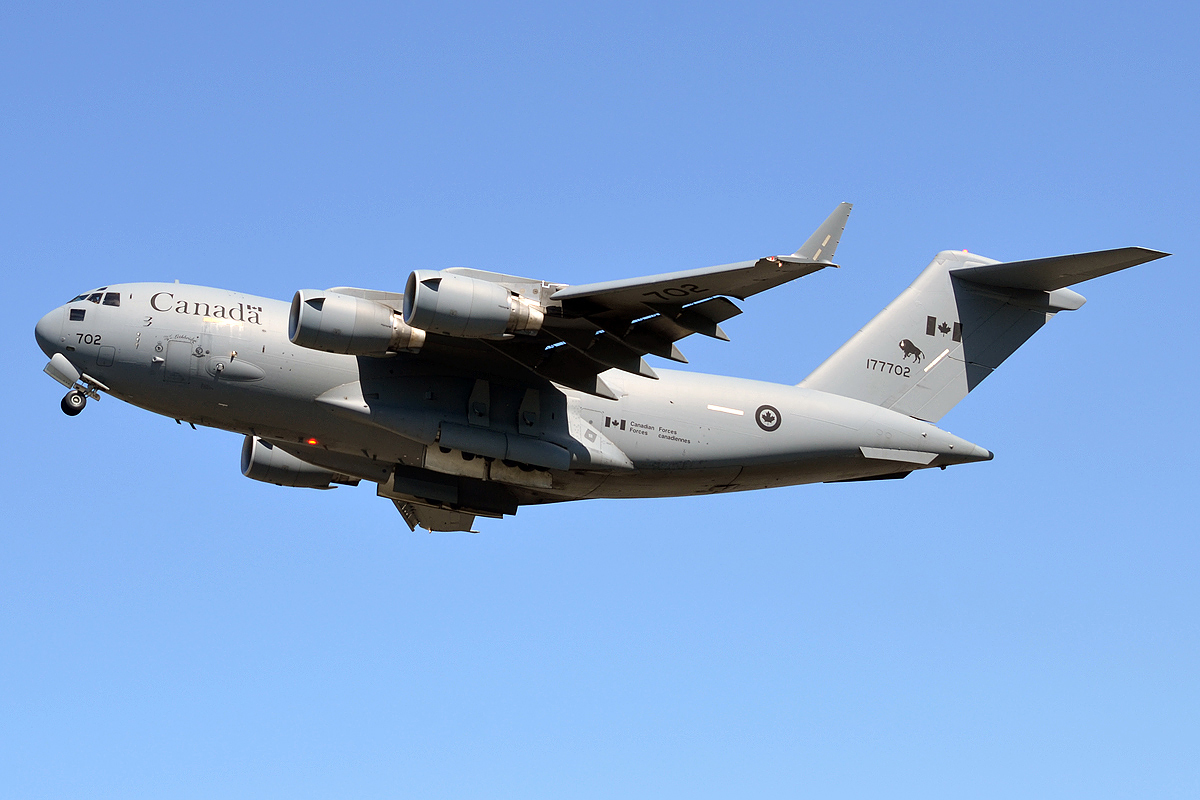 A Canadian CC-177 Globemaster III transport aircraft in flight against a blue sky.