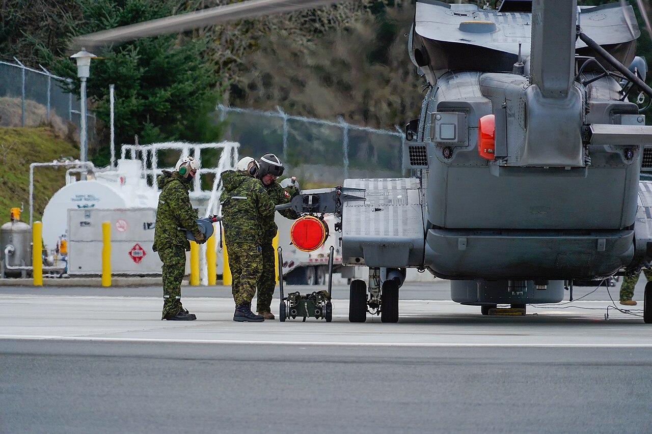 Personnel load an exercise torpedo onto a CH-148 Cyclone at a Canadian test facility.